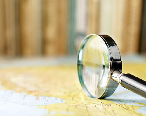magnifying glass on the map and book in the background in the area of confusion